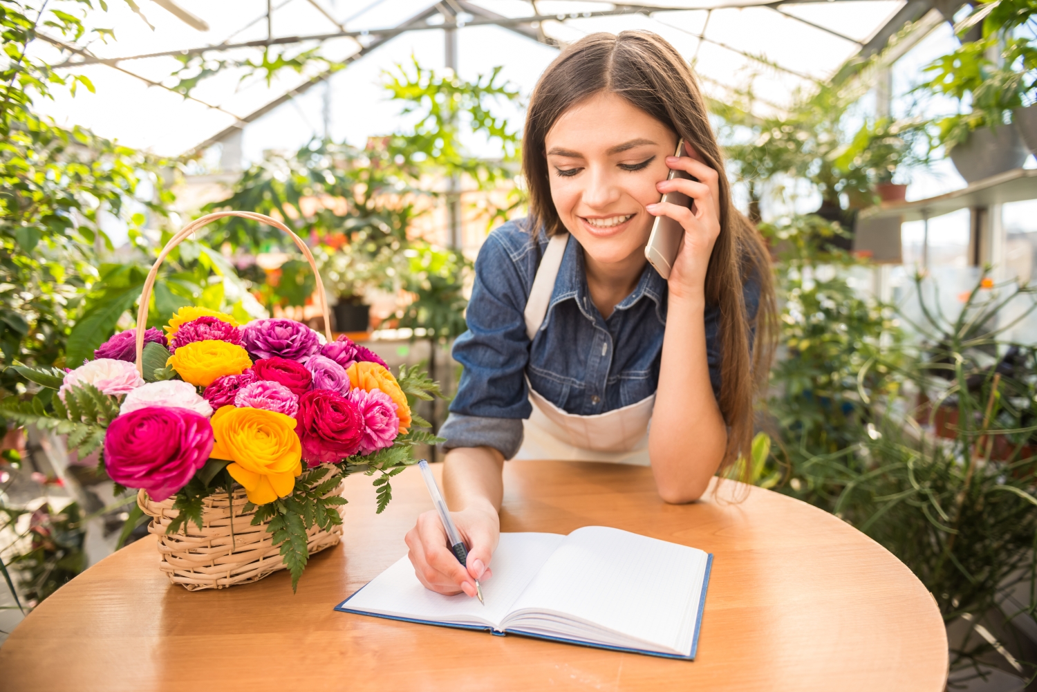 This is image of a cheerful flower shop business owner chatting with a client on the phone